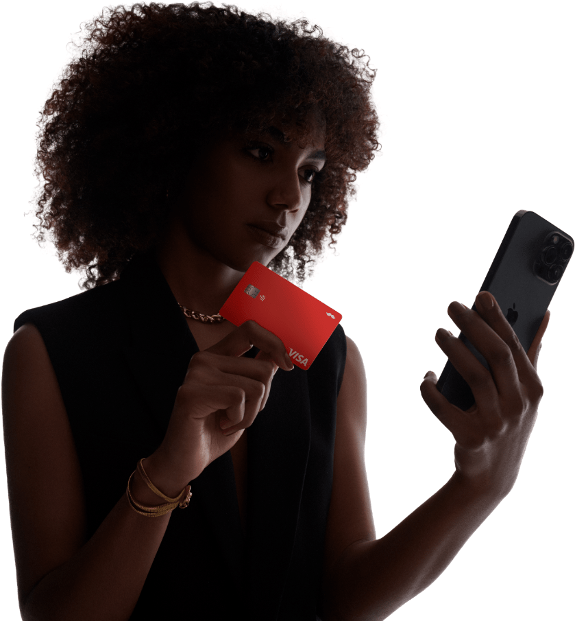 Mujer sosteniendo tarjeta débito RappiPay y mirando celular